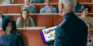 Academic in front of students holding laptop with Kortext on screen