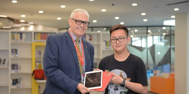 A student receives a new iPad from BUV’s Chief Academic Officer Christopher Jeffery
