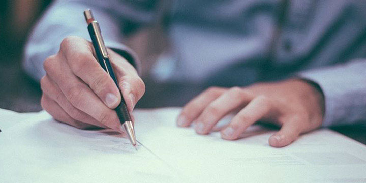 man signs paper with a pen