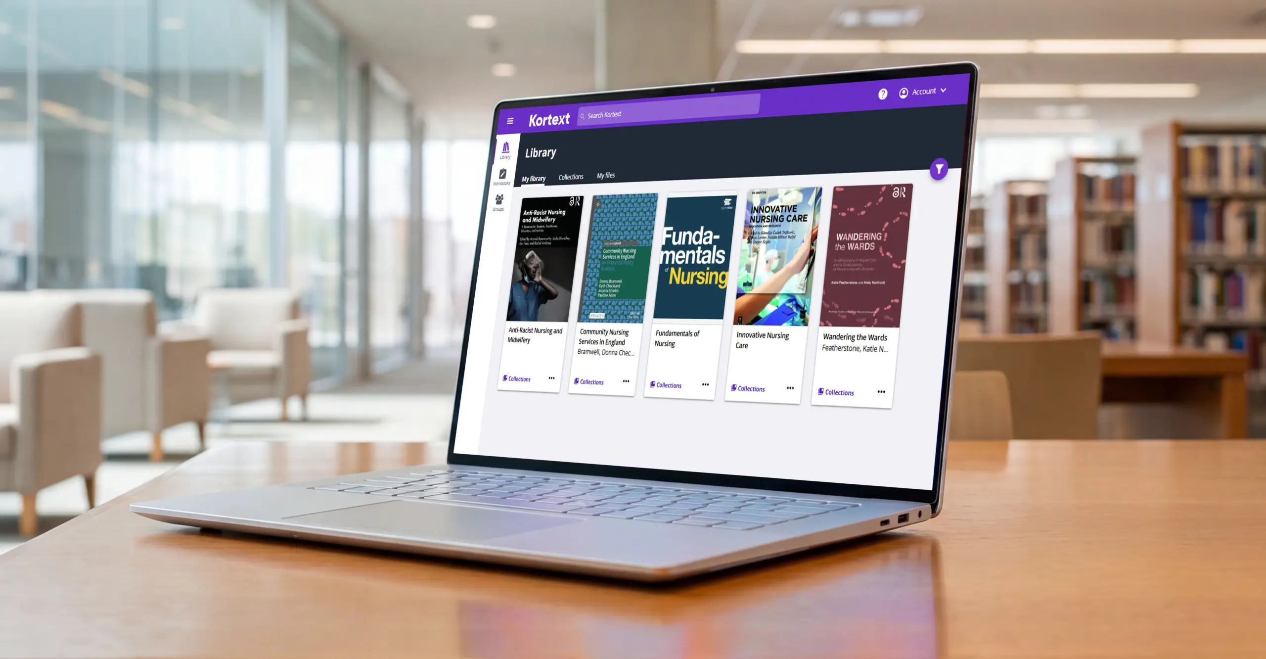 A laptop on a desk in a library displaying the Kortext platform, showing a curated collection of nursing ebooks in the library view.