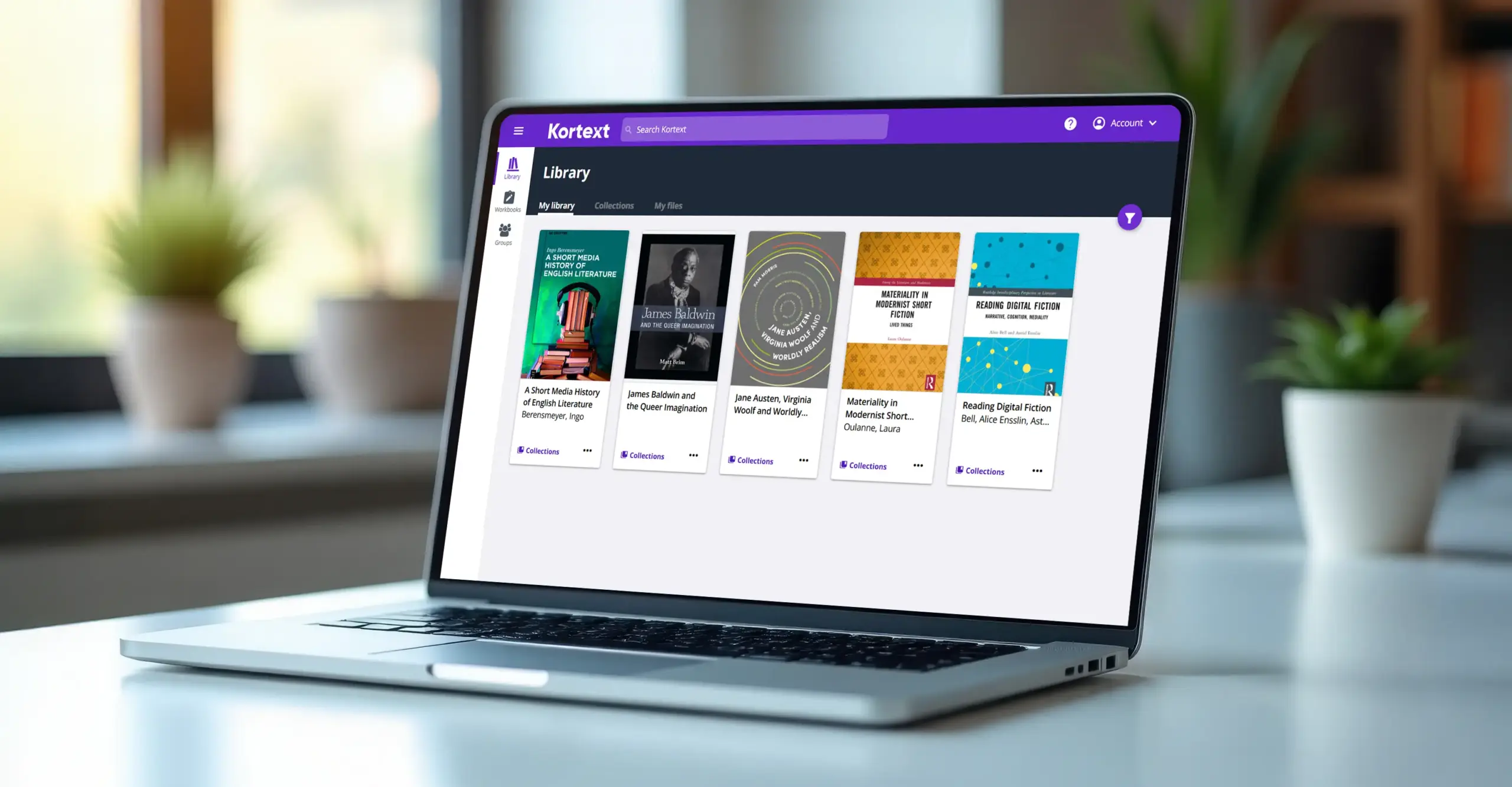 Laptop on a desk displaying the Kortext library with a collection of academic eBooks on screen