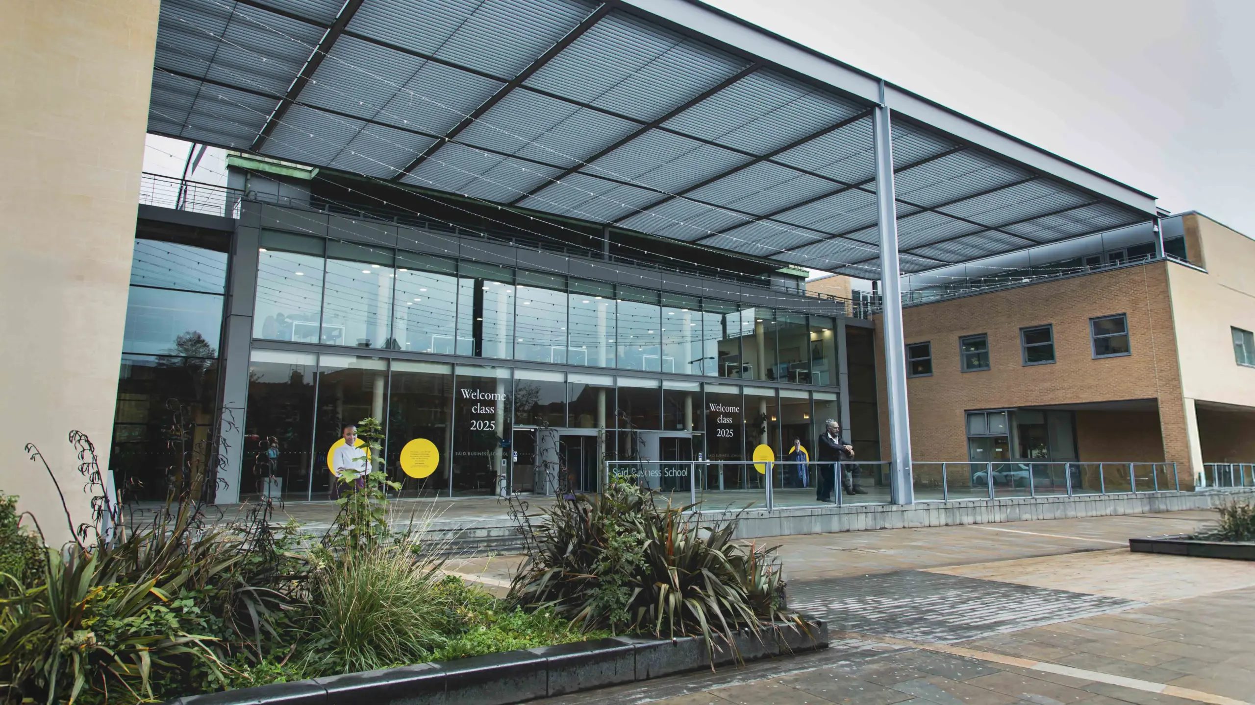 Exterior of Saïd Business School, University of Oxford, with glass frontage displaying 