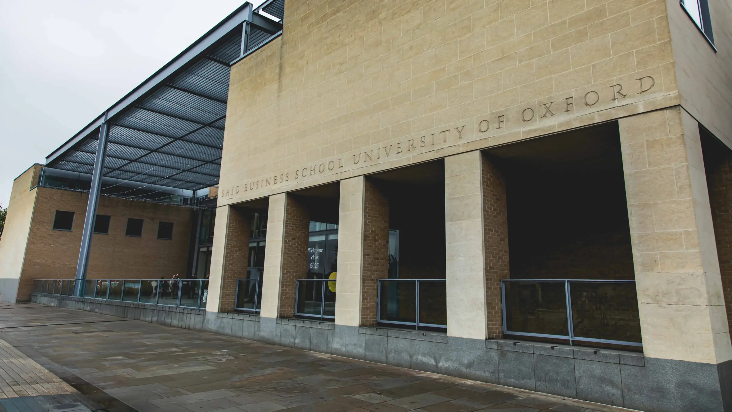 The exterior stone facade of Saïd Business School University of Oxford, with carved lettering above a colonnade entrance.
