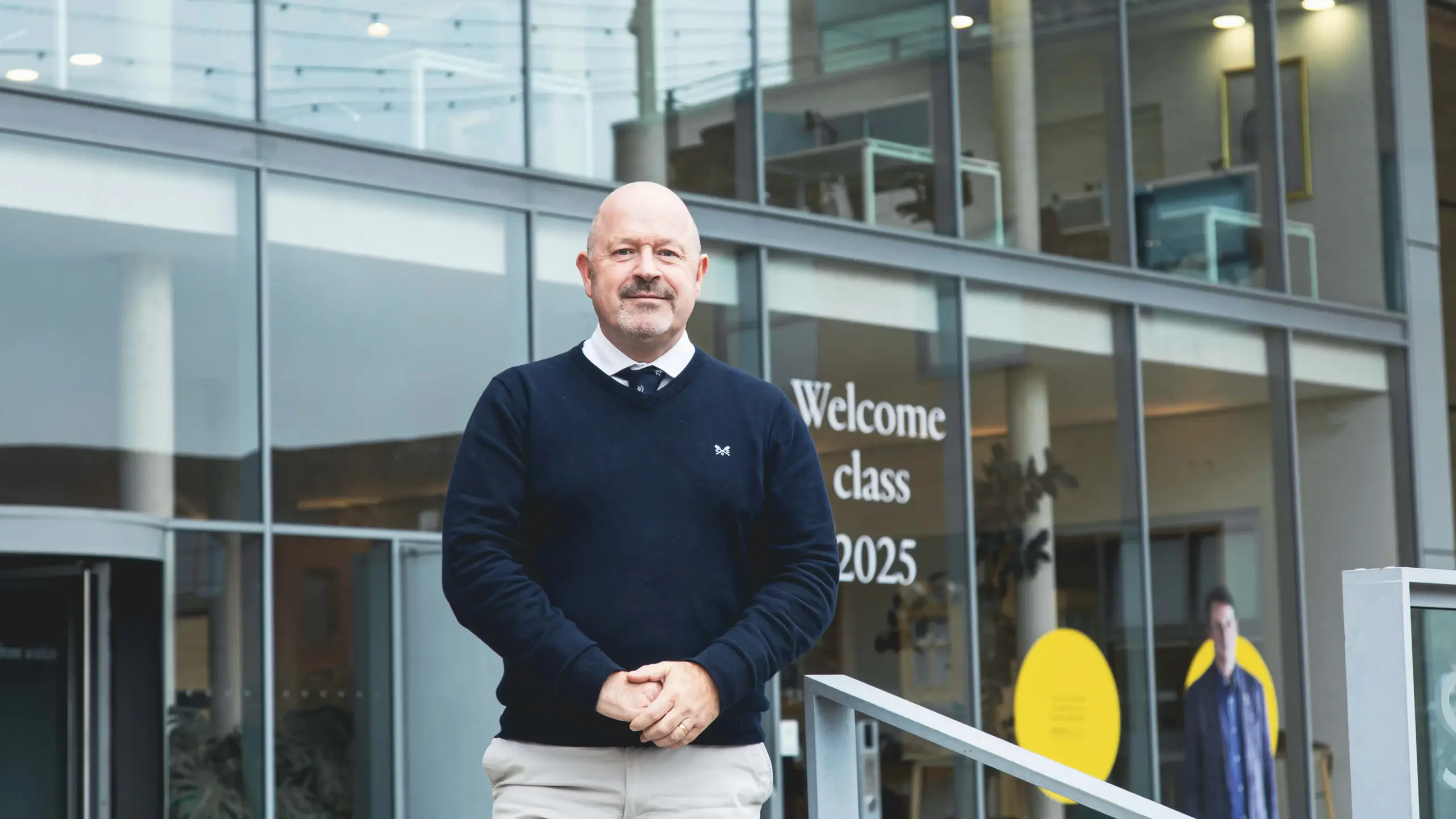 Mark Bramwell, Chief Digital Information Officer at Saïd Business School and Director of Strategic Digital Partnerships, standing in front of the glass entrance to Saïd Business School.