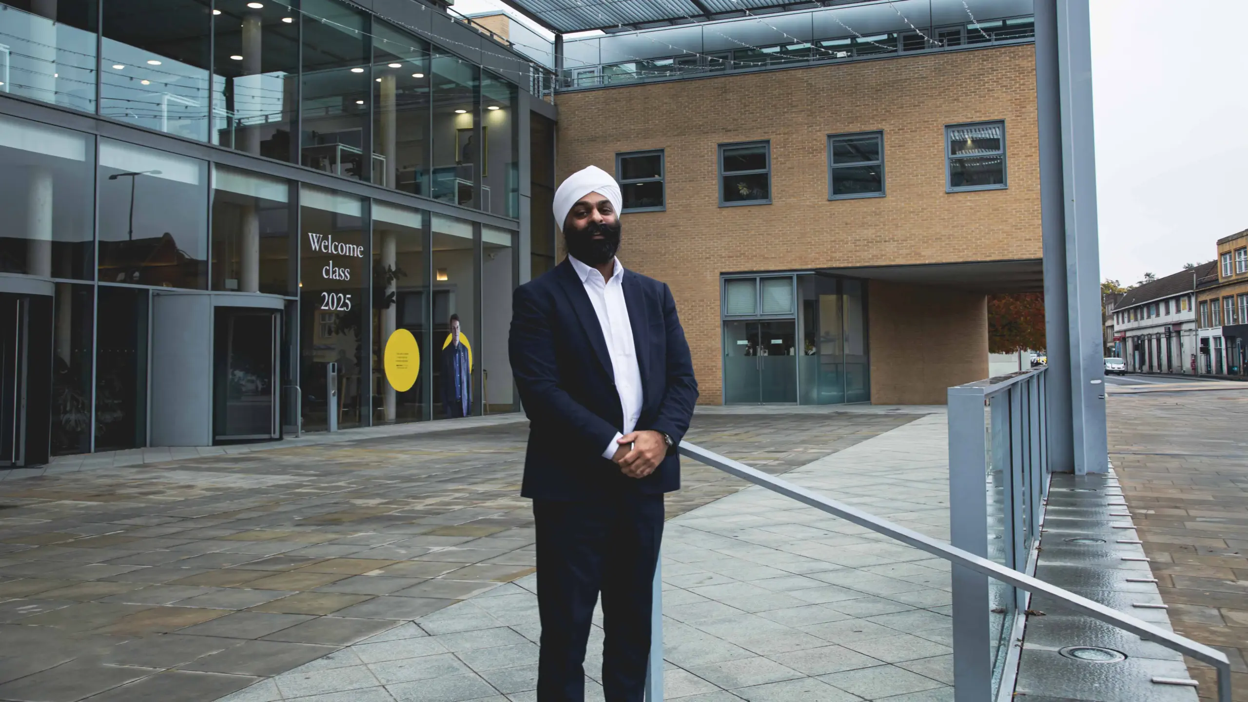 Jyotveer Gill, Associate Director for Education Technology and Web Development standing in front of the glass entrance to Saïd Business School.