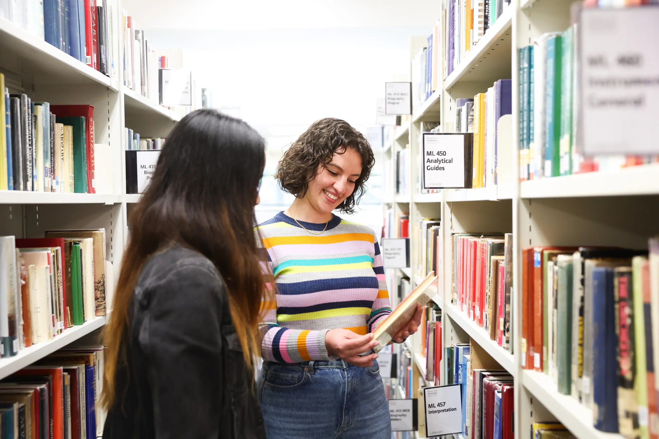 A member of the RNCM library team helps a student find their book.