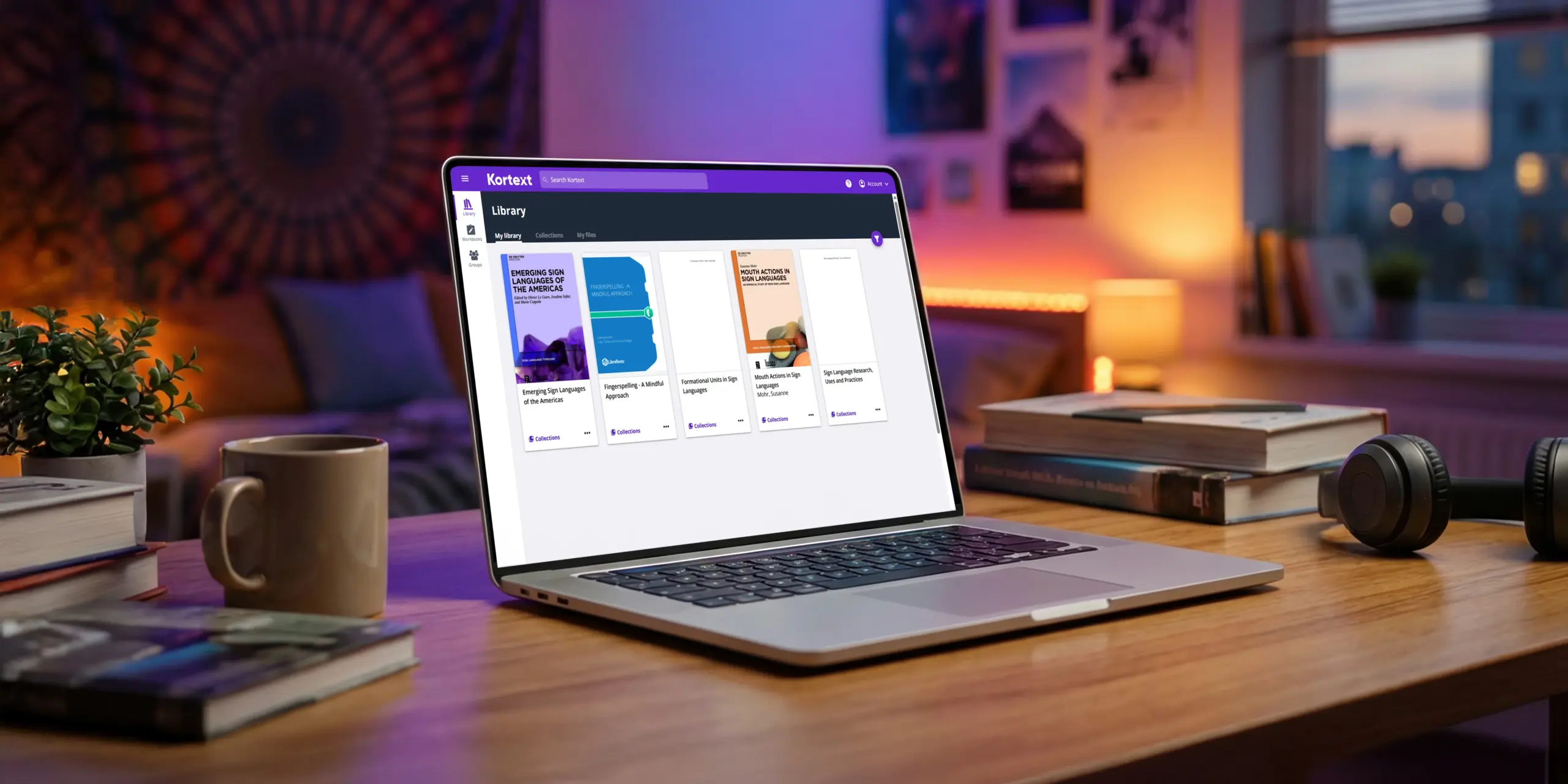 A laptop on a desk displaying the Kortext library, showing the five sign language OER book covers.
