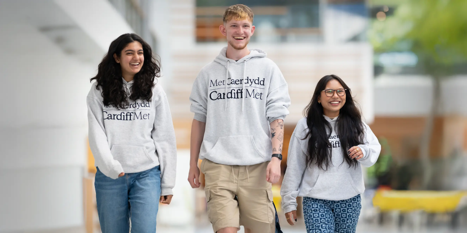 3 Cardiff Met students looking happy and walking together on campus