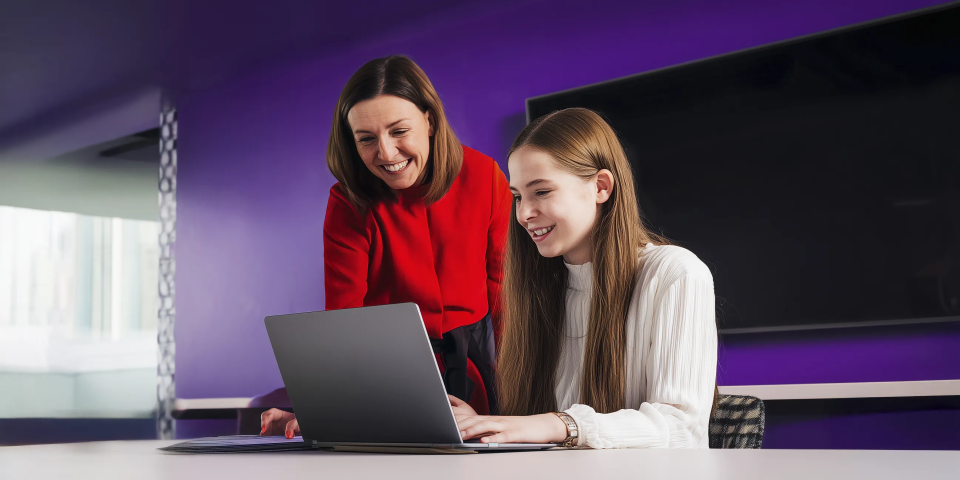 Personal tutor and her student are smiling together at a laptop screen