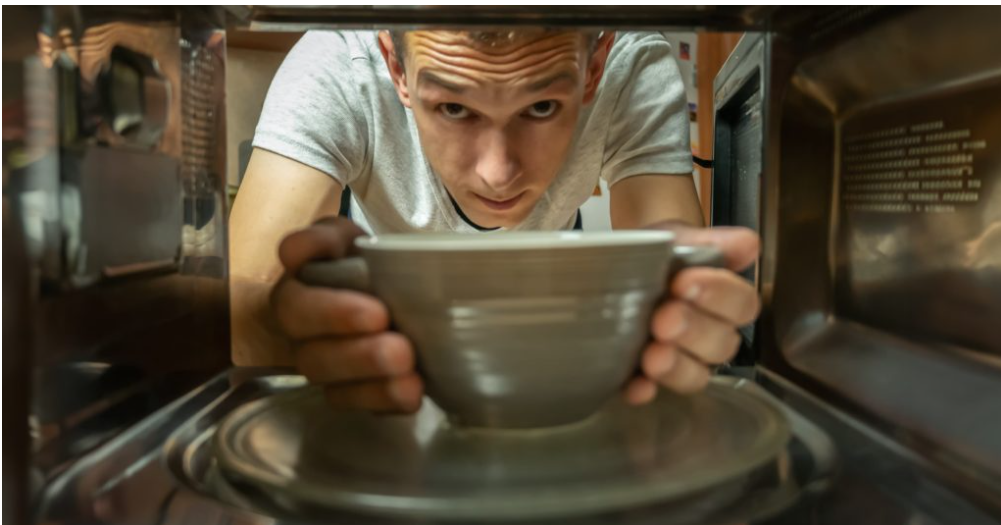 student taking mug out of microwave